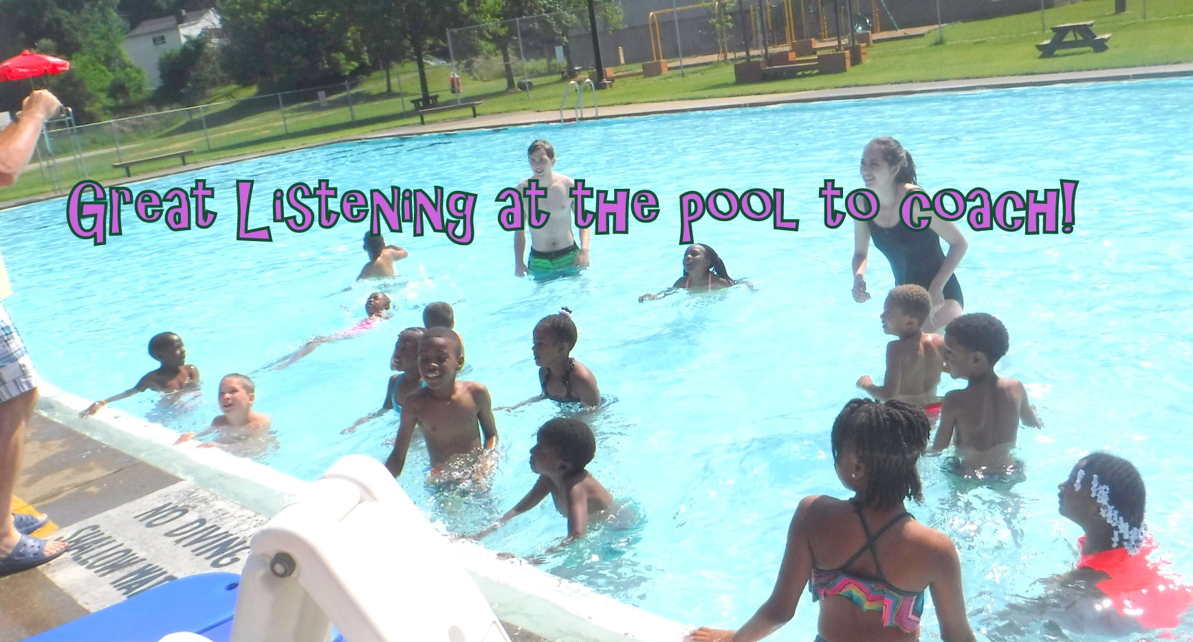 Swimmers in pool listen to coach.